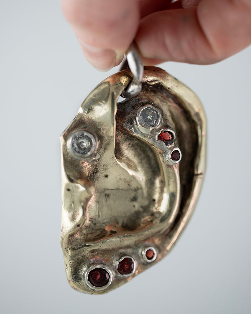 Ear pendant. Brass, 5 garnet stones, 2 zircons. / Wisior w kształcie ucha. Mosiadz, 5 kamieni granatów, 2 cyrkonie.