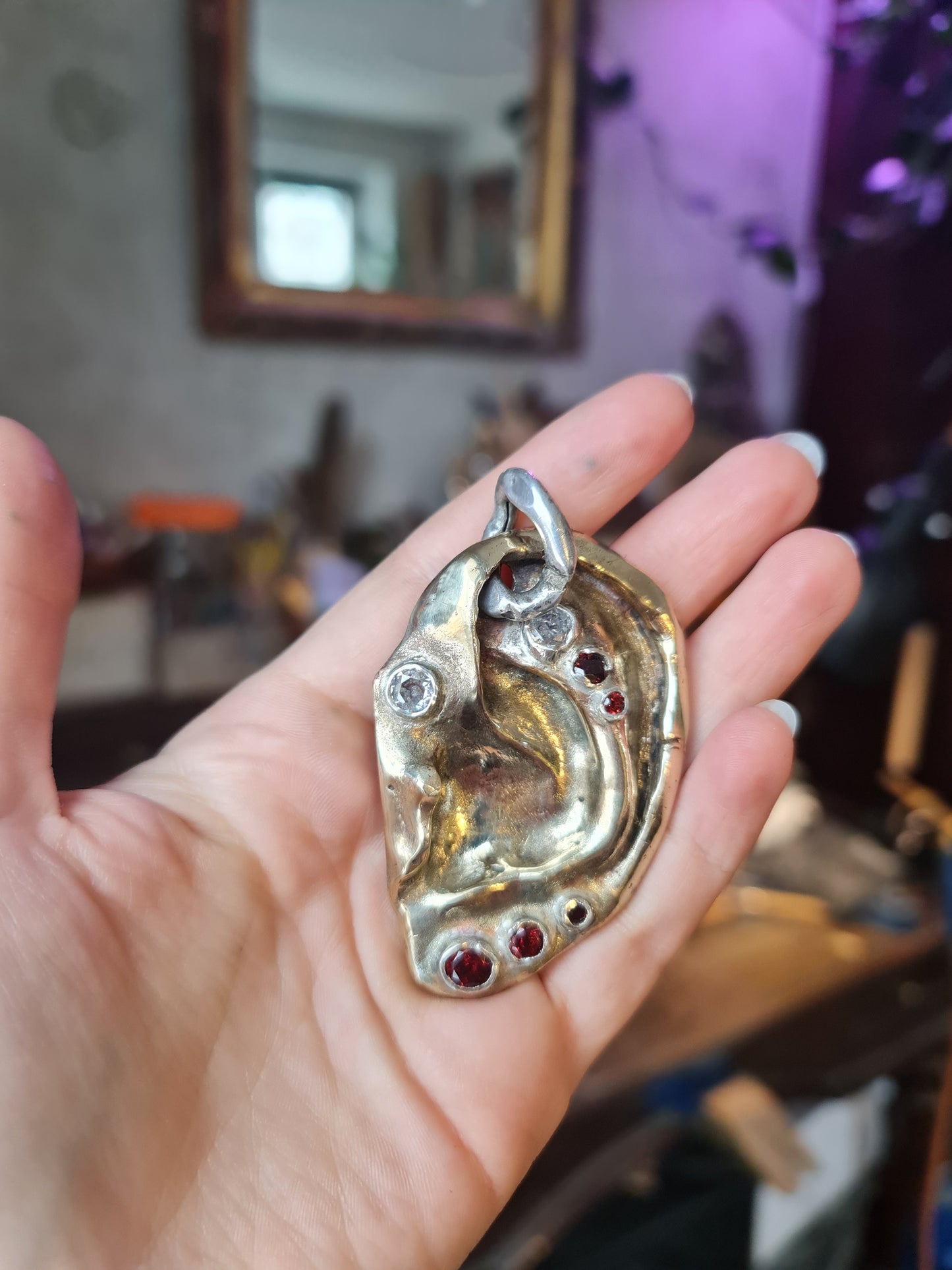 Ear pendant. Brass, 5 garnet stones, 2 zircons. / Wisior w kształcie ucha. Mosiadz, 5 kamieni granatów, 2 cyrkonie.